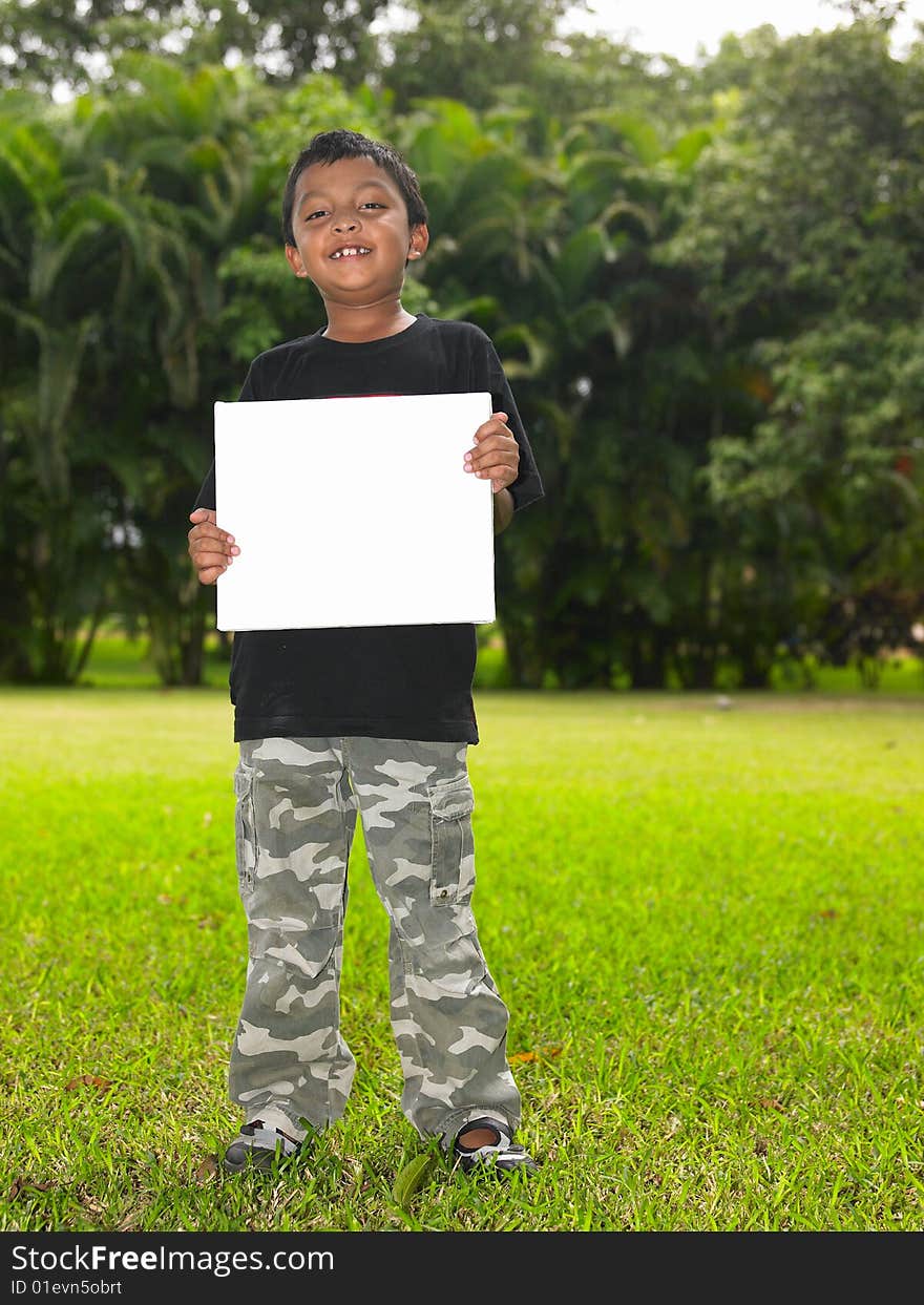 Boy with a blank placard in the garden