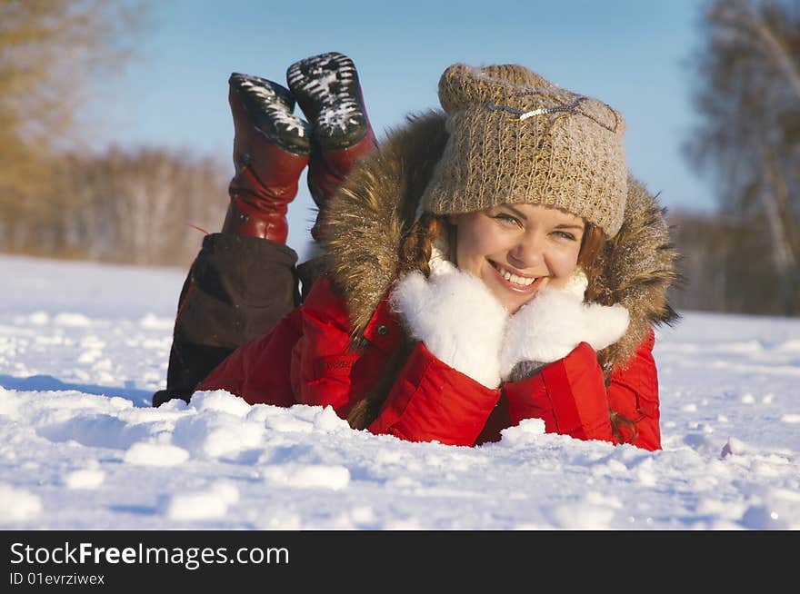 Attractive girl lays on snow and smiles