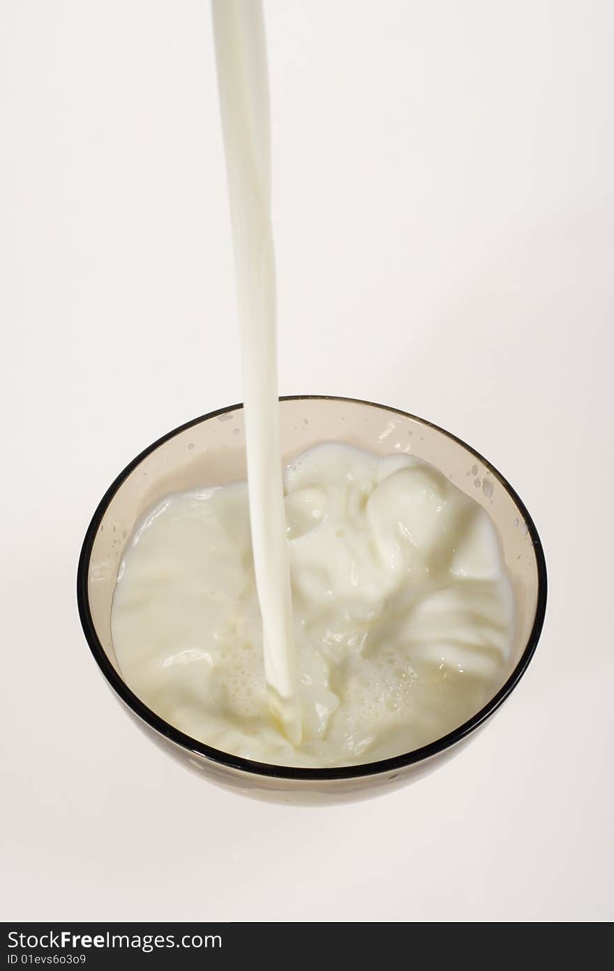 Pouring milk into glass bowl on white background. Pouring milk into glass bowl on white background