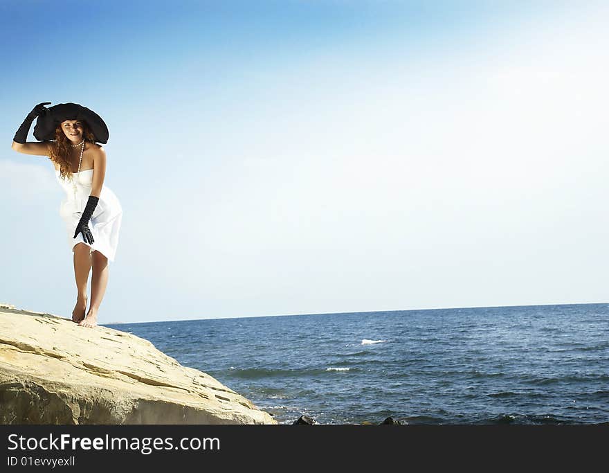 Beautiful girl in the large black hat of sunburn on a beach. Beautiful girl in the large black hat of sunburn on a beach