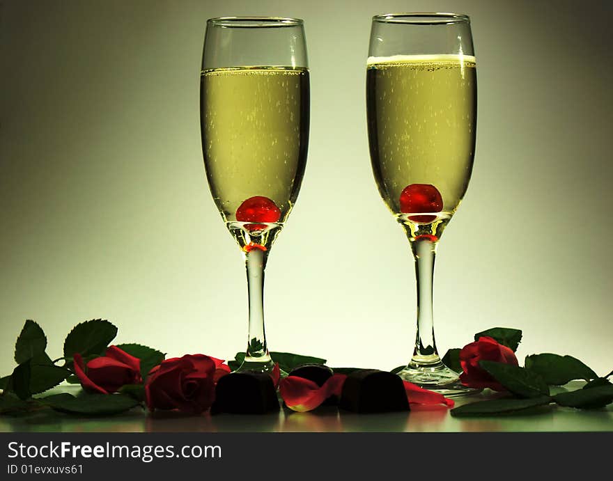 Two glasses of champagne, cherries, chocolate, roses and romantic lighting. Two glasses of champagne, cherries, chocolate, roses and romantic lighting.