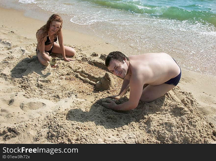 The beautiful man and woman play sand. The beautiful man and woman play sand