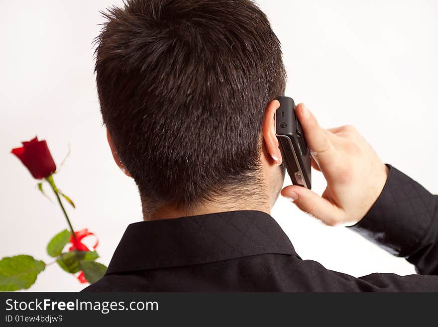 Man arranging a date via telephone and holding a rose. Man arranging a date via telephone and holding a rose