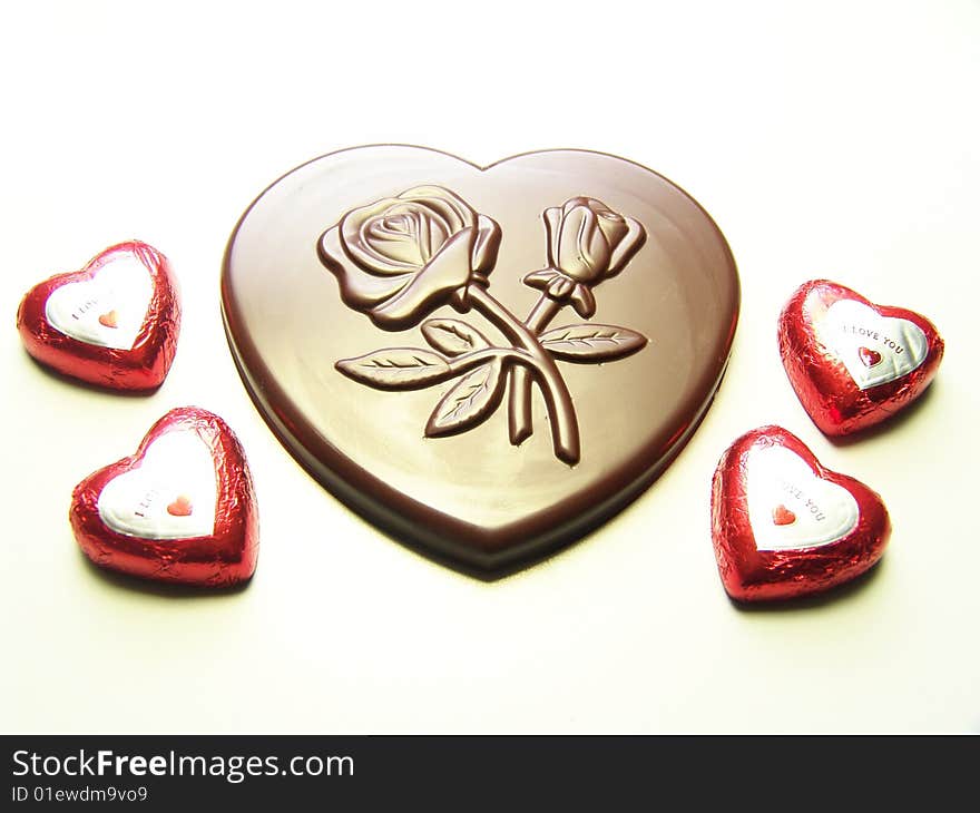 Heart and lips chocolates wrapped in red paper and a big heart chocolate with embossed flowers on it