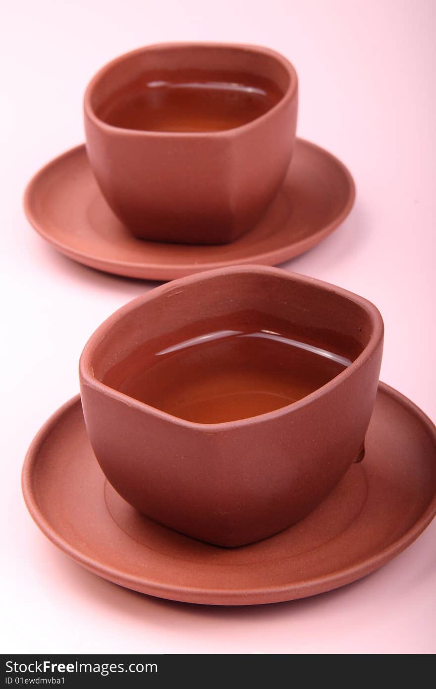 Two cups of tea are on the white and pink background. This is traditional Chinese tea. Two cups of tea are on the white and pink background. This is traditional Chinese tea.