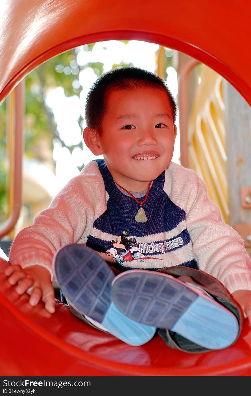 asian boy playing the sliding board