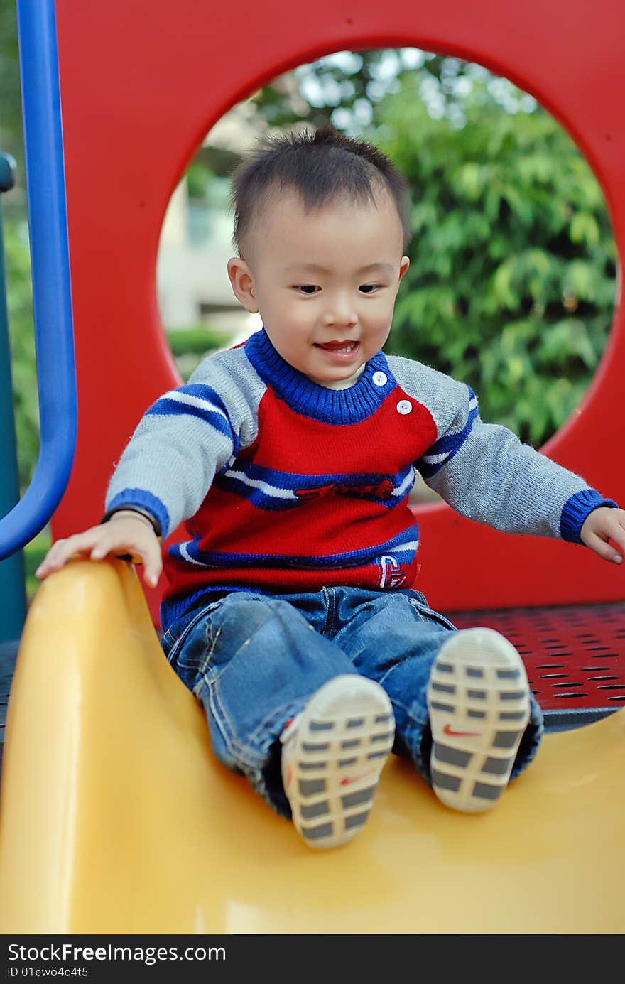 The child playing the sliding board. The child playing the sliding board