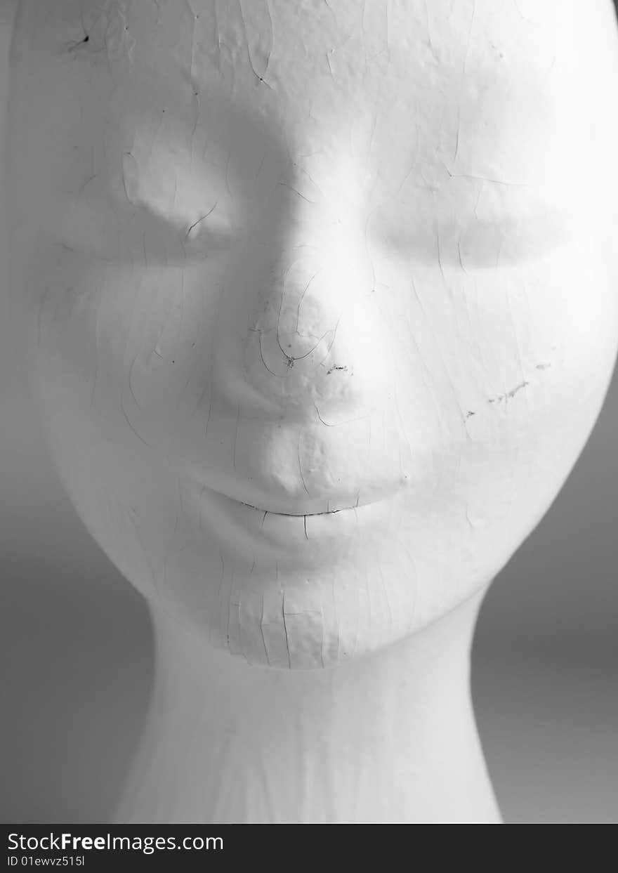 A head of an old female mannequin fashion head painted white, worn and used with cracks and scratches. A head of an old female mannequin fashion head painted white, worn and used with cracks and scratches.