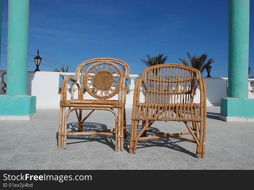 Wattled chairs on a verandah at a sea