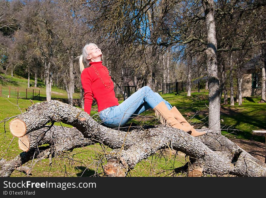 Attractive blond girl sitting on downed oak tree. Attractive blond girl sitting on downed oak tree.