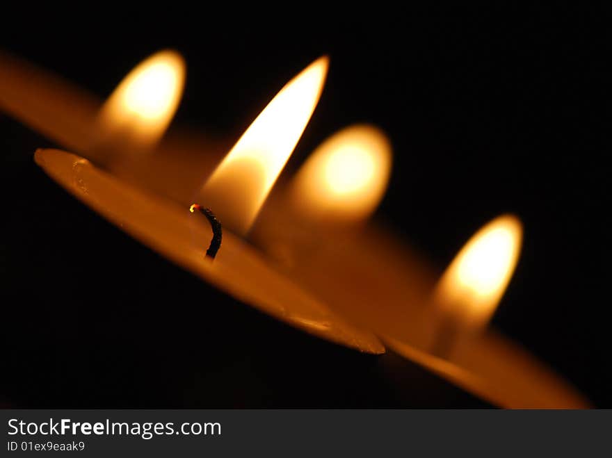 4 candles. In the foreground a candle in focus