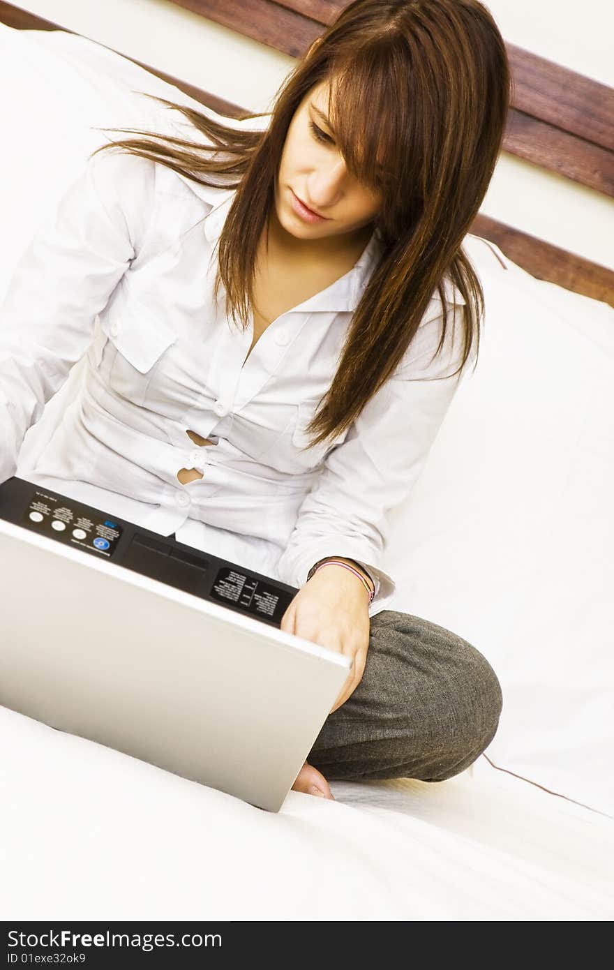 Young smiling businesswoman using laptop in bed. Young smiling businesswoman using laptop in bed