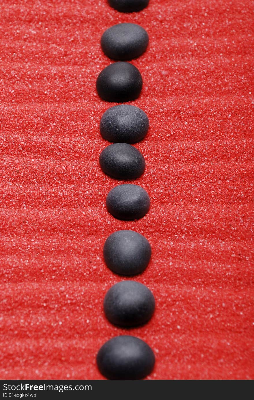 Line from black stones on red sand