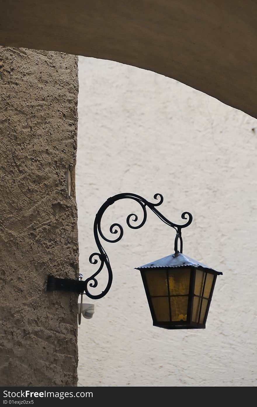 Historic lantern on a stone facade in an arch. Historic lantern on a stone facade in an arch