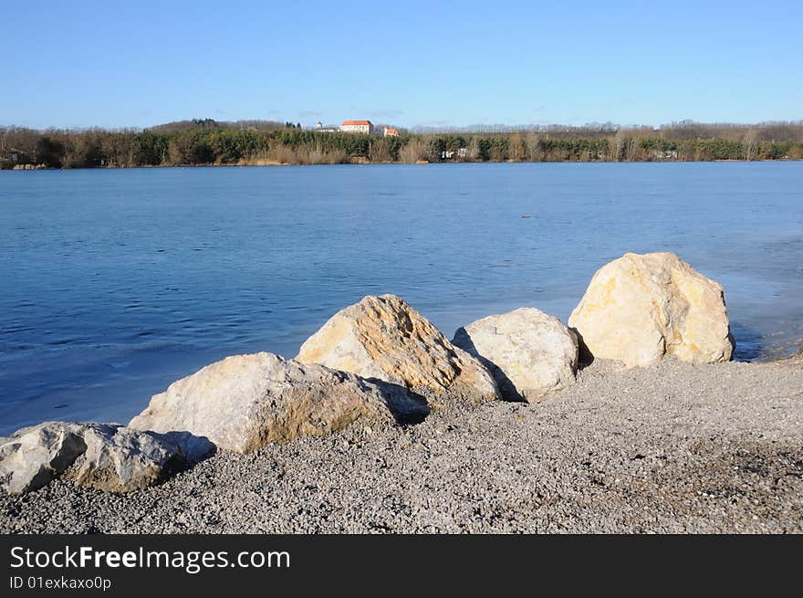 Frozen lake in winter with blue sky and rocks. Frozen lake in winter with blue sky and rocks