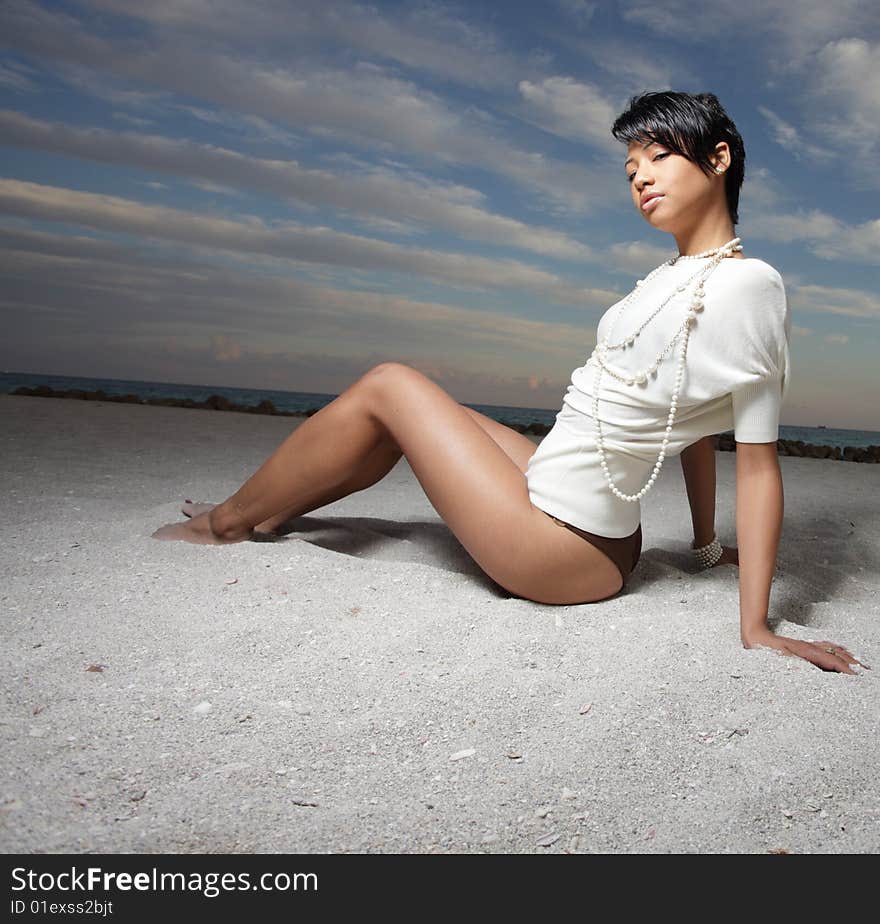 Beautiful young woman sitting on the sand. Beautiful young woman sitting on the sand