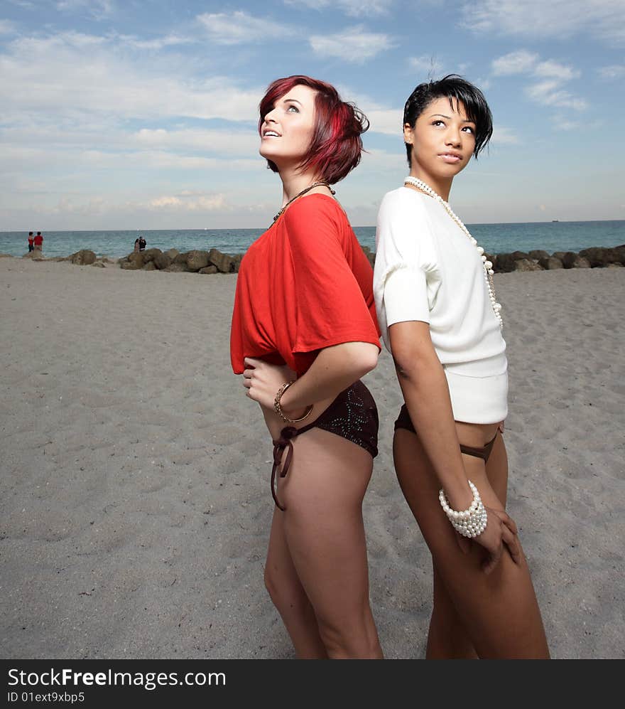 Two beautiful young women on the sand looking at a light from above. Two beautiful young women on the sand looking at a light from above