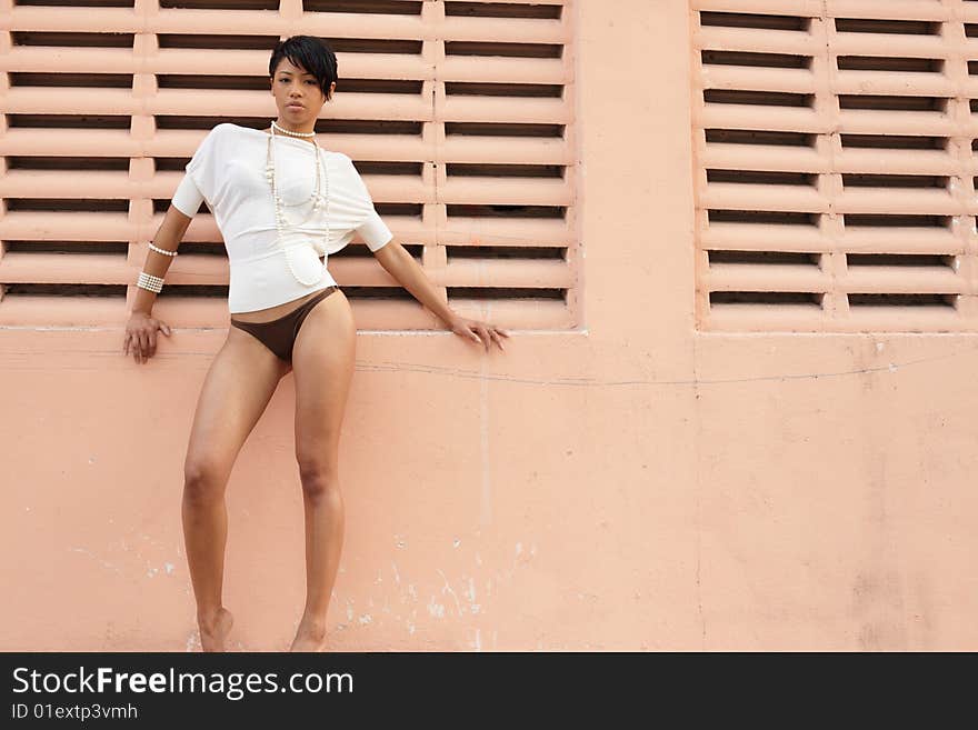 Beautiful young woman posing by a  wall. Beautiful young woman posing by a  wall