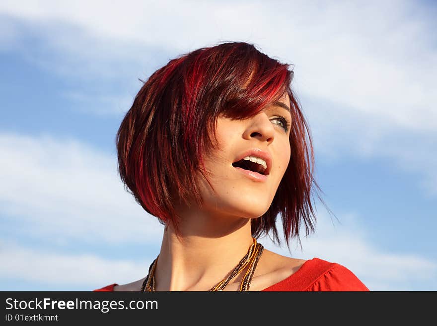 Beautiful young woman on a cloudy blue sky background. Beautiful young woman on a cloudy blue sky background