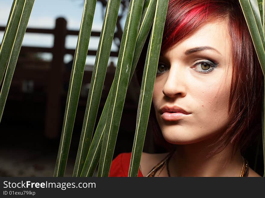 Headshot of a woman posing by green palm fronds. Headshot of a woman posing by green palm fronds