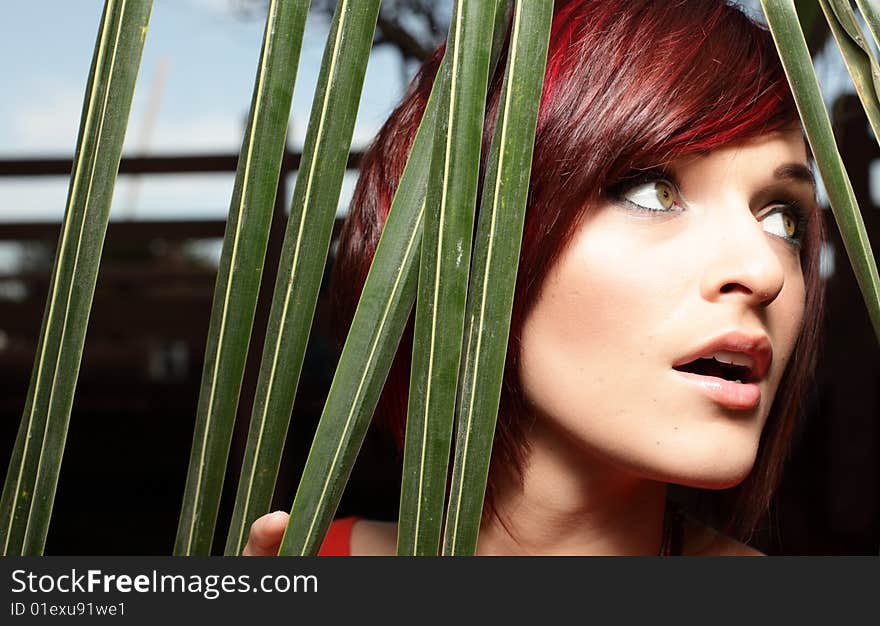 Headshot of a woman posing by green palm fronds. Headshot of a woman posing by green palm fronds