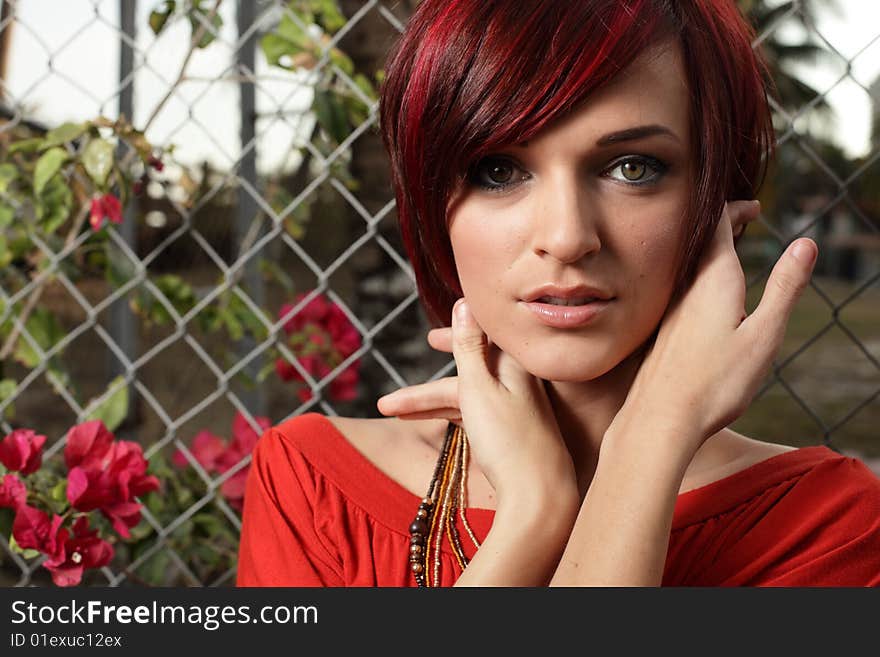 Headshot of a woman posing by a fence. Headshot of a woman posing by a fence