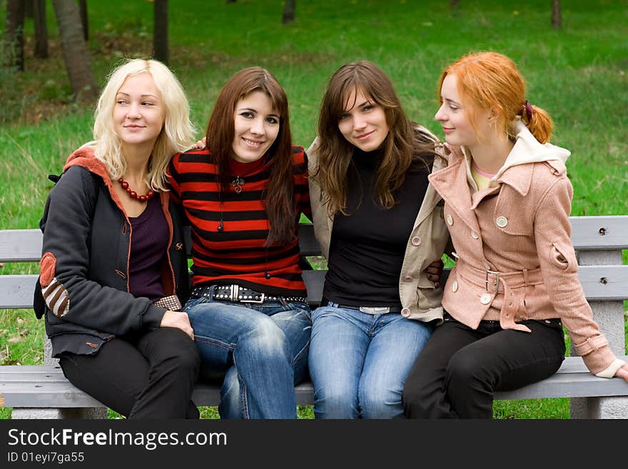 Four girls sitting on a park bench