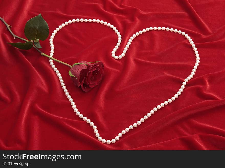 Rose and heart of beads on red fabric.