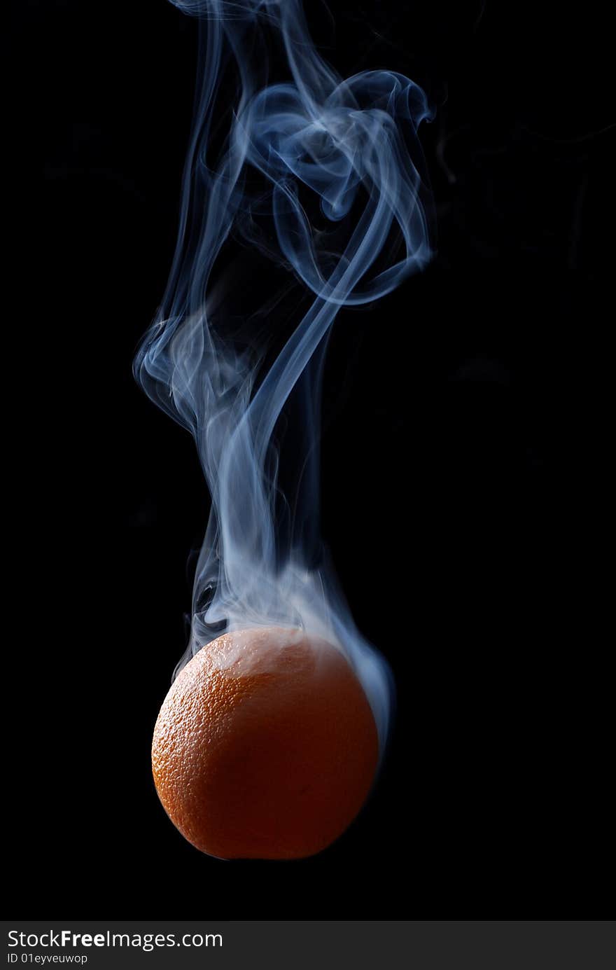 Orange enveloped by smoke on a black background. Orange enveloped by smoke on a black background