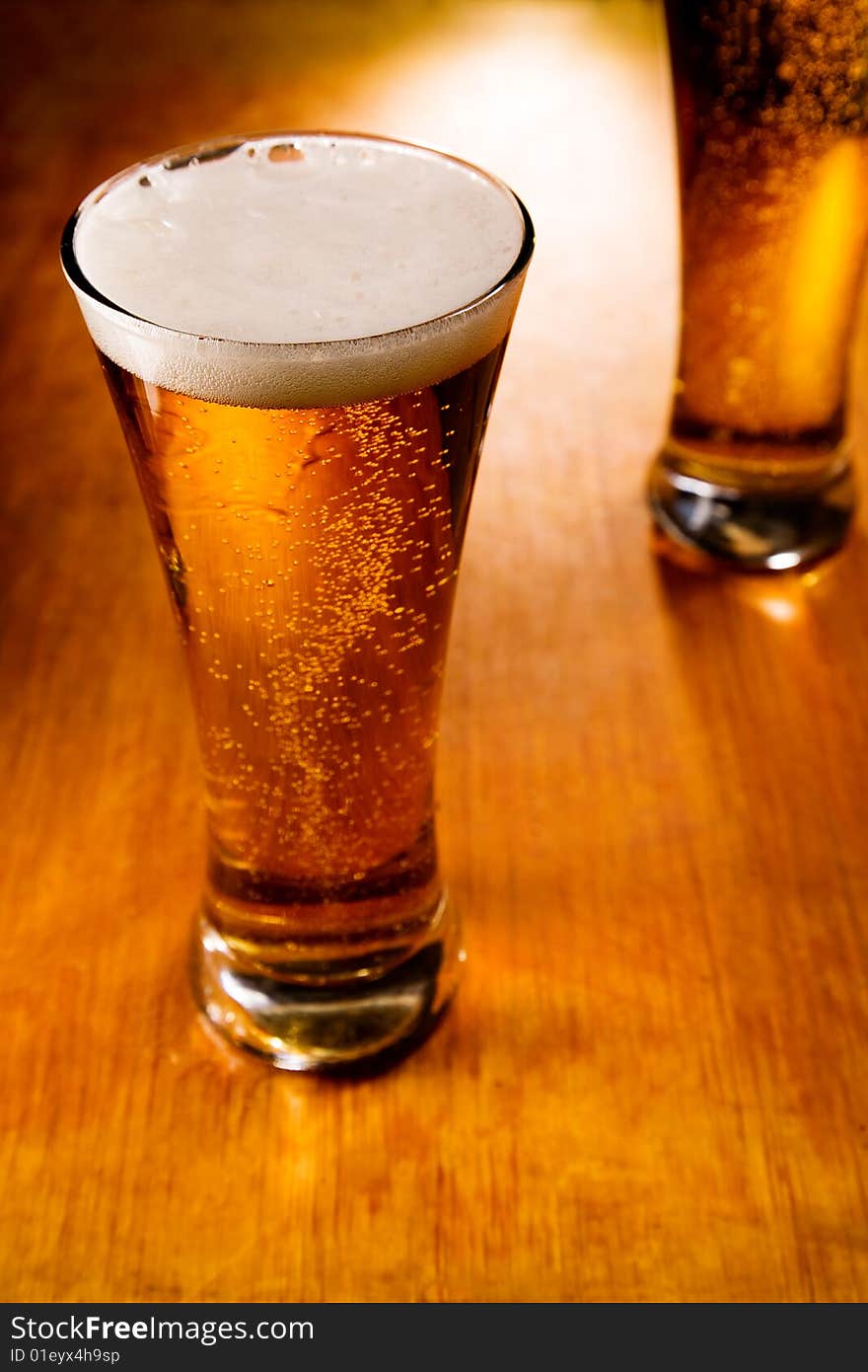 Two beer glasses on wood background, selective focus. Two beer glasses on wood background, selective focus