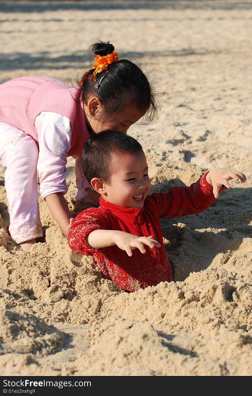 Young Kids Playing Burying Games in the sunny beach