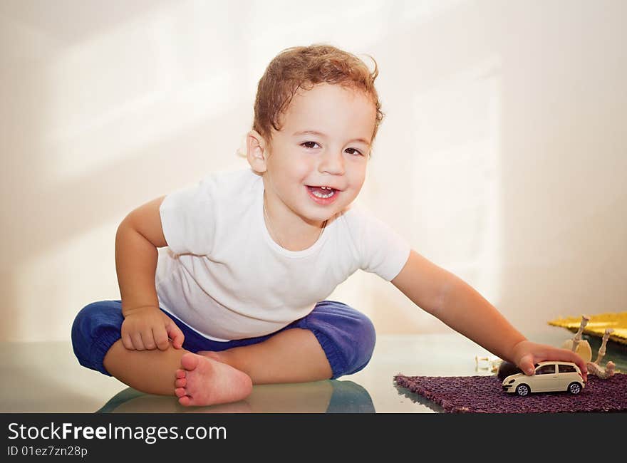 Small boy playing with a toy car on glass table