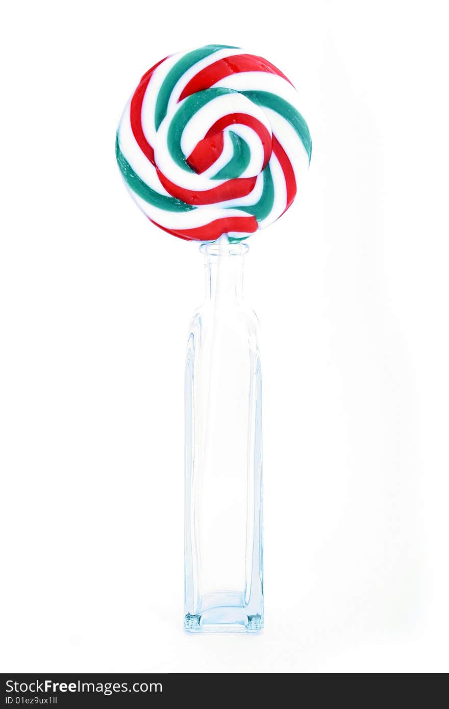 One single handmade lollipop in a clear bottle on a white background. One single handmade lollipop in a clear bottle on a white background.