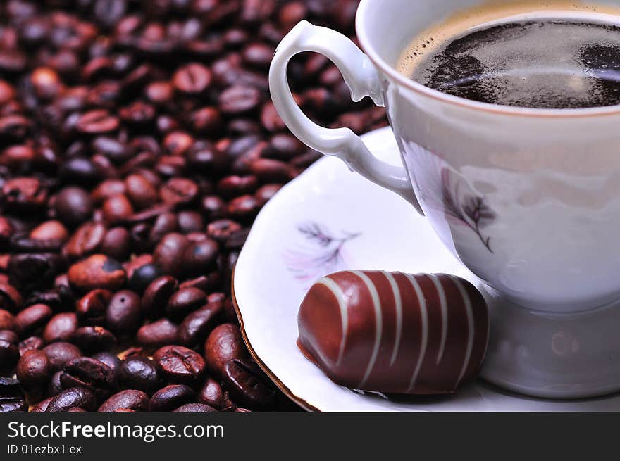 A cup of coffee with chocolate on beans. A cup of coffee with chocolate on beans