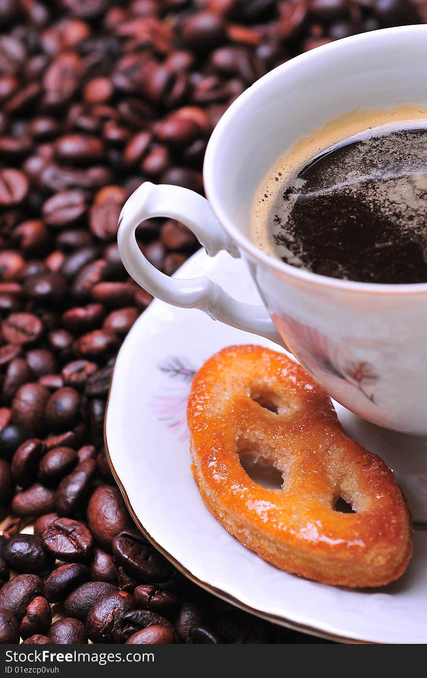 A cup of coffee with cookie on beans. A cup of coffee with cookie on beans