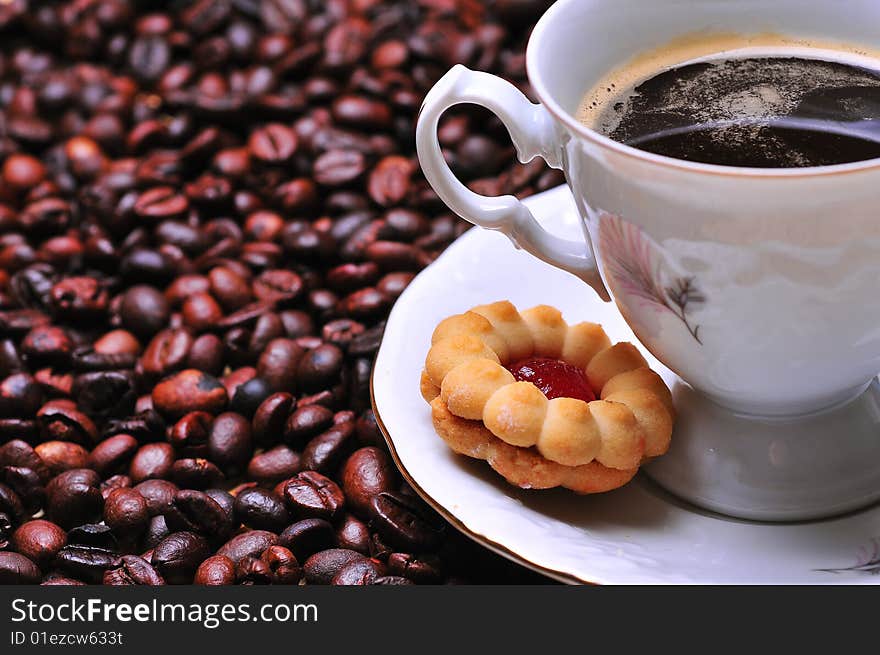 A cup of coffee with cookie on beans. A cup of coffee with cookie on beans