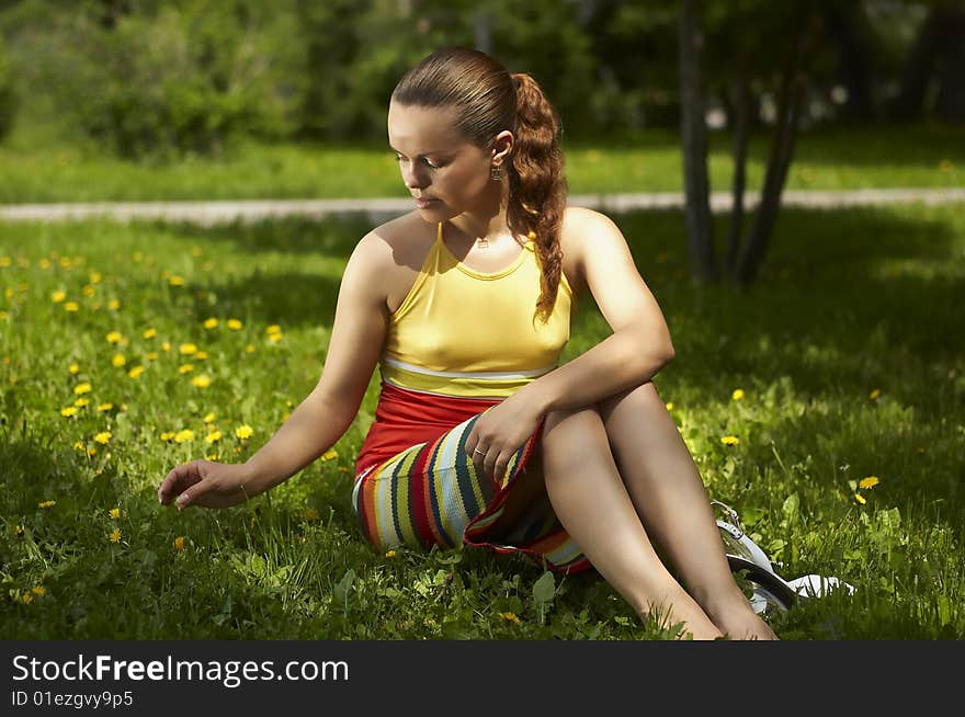 The girl sits on a grass and has a rest. The girl sits on a grass and has a rest