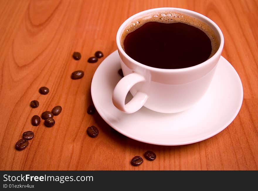 Cup of coffee and beans on wooden table