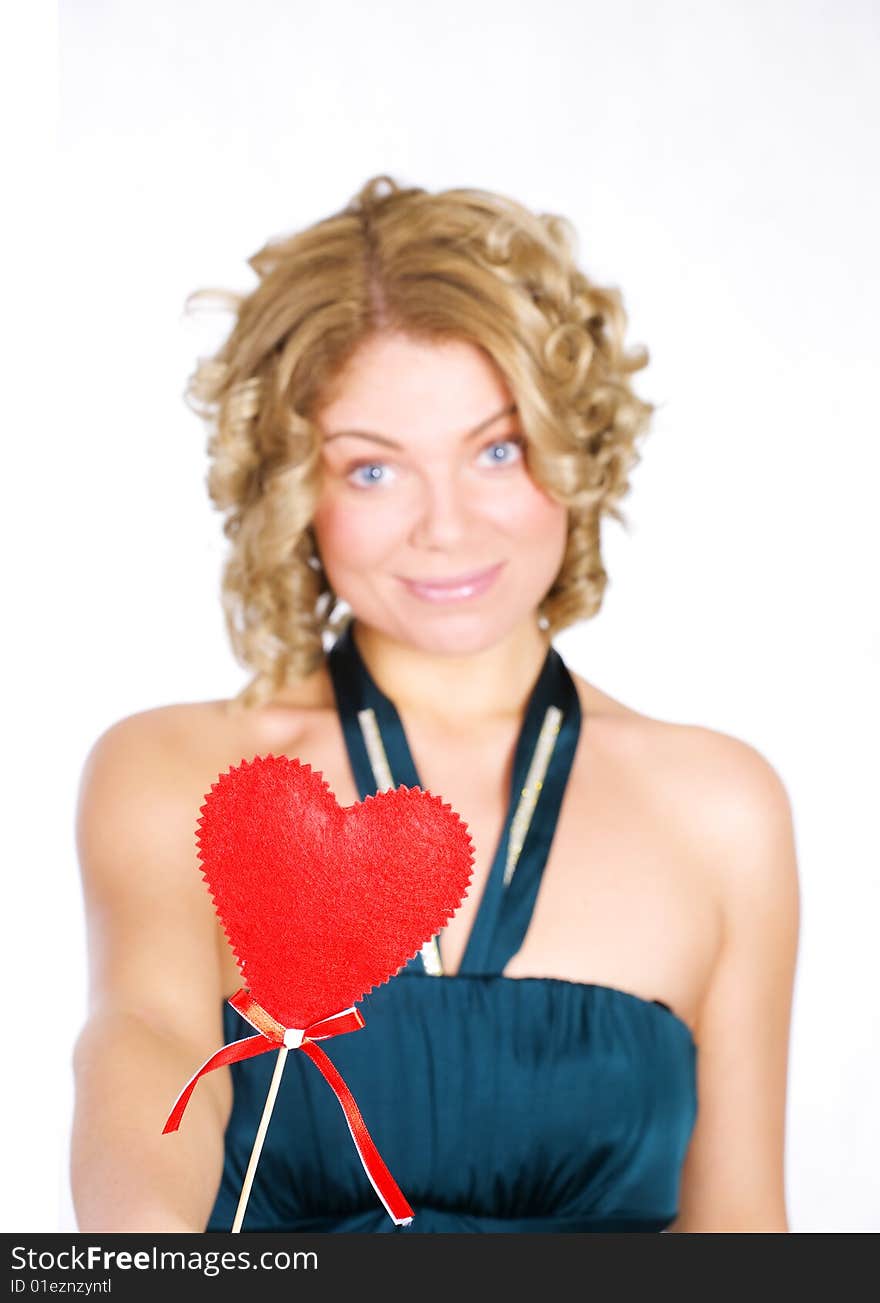 Young blond holding a red heart. Isolated over white. Focus on the heart.