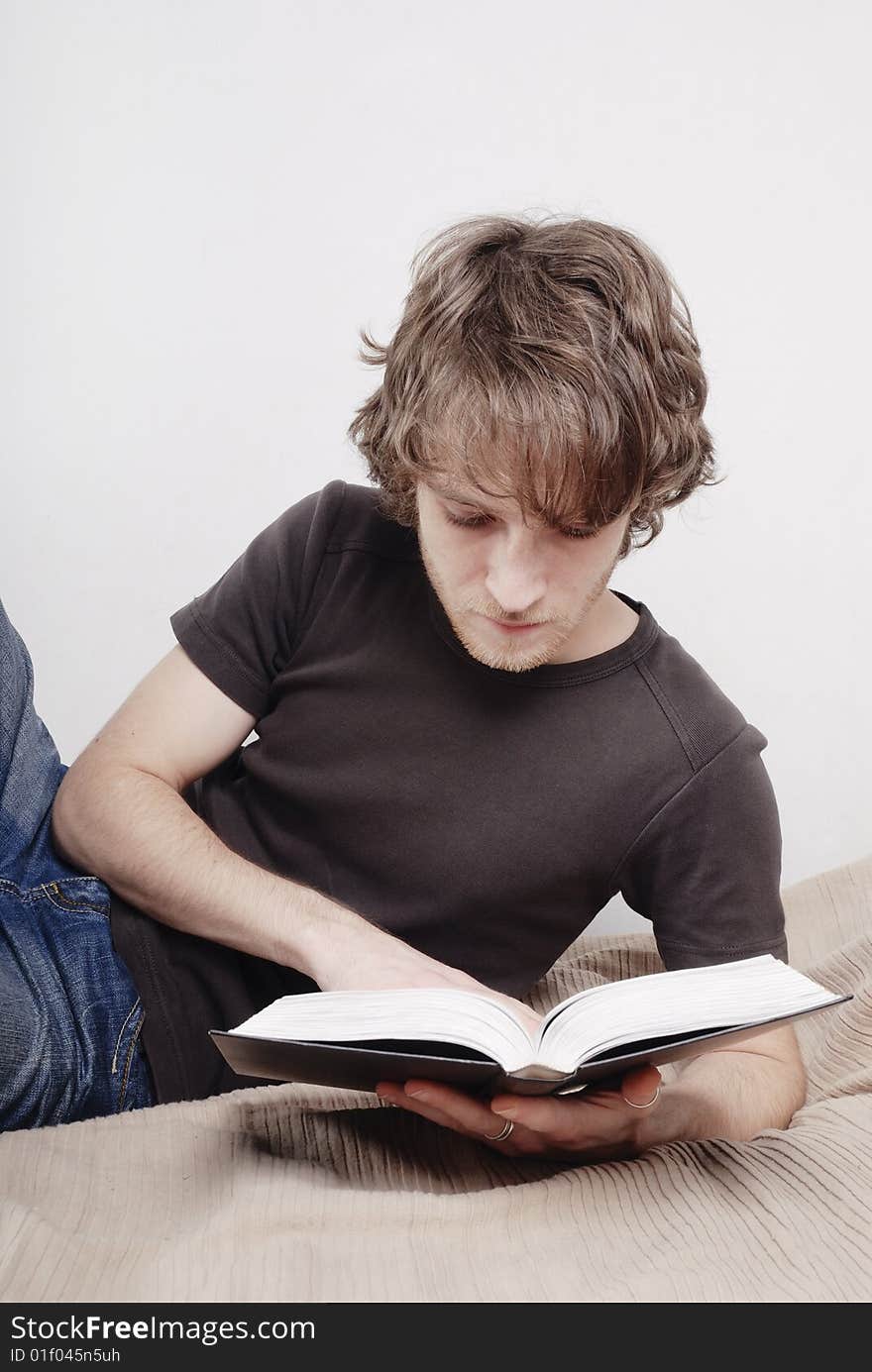 Young man reads the book on a bed