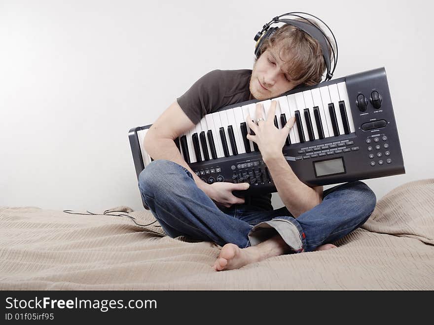 Man in the brown T-shirt hugs a MIDI-keyboard. Man in the brown T-shirt hugs a MIDI-keyboard