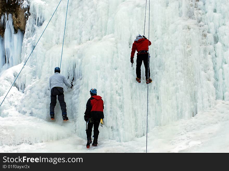 Three men climb frozen waterfall. Three men climb frozen waterfall