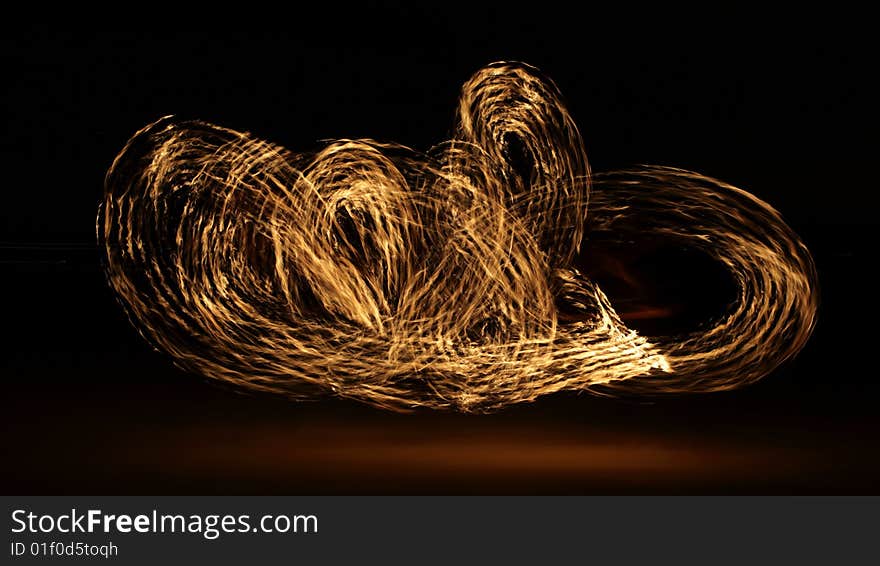 Fire dancer making circles of fire on the beach. Fire dancer making circles of fire on the beach