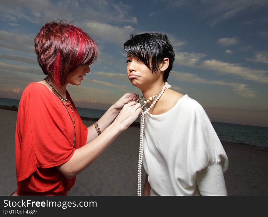 One woman fixing another woman's necklace. One woman fixing another woman's necklace