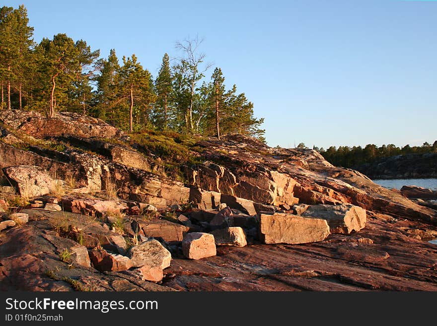 Summer sunrise with forest, water and rocks