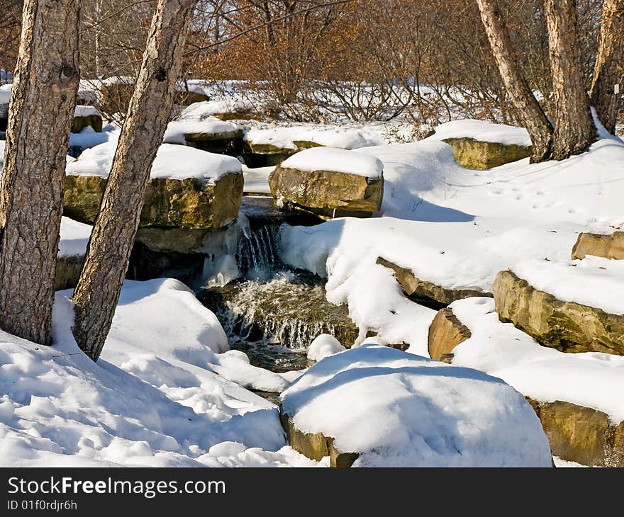 A snowy creek with a small waterfall