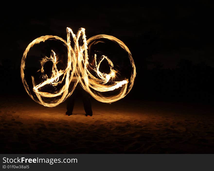 Fire dancer making circles of fire on the beach. Fire dancer making circles of fire on the beach