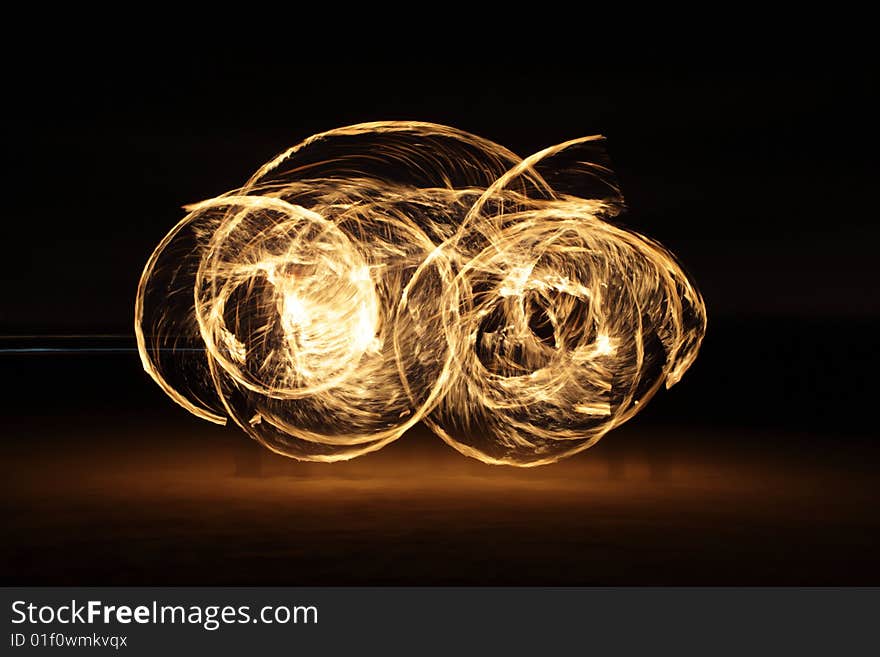 Fire dancer making circles of fire on the beach. Fire dancer making circles of fire on the beach