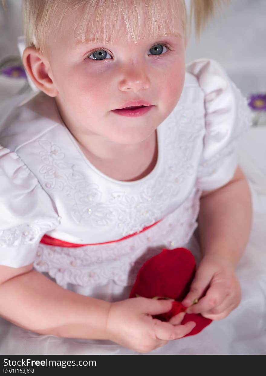 Child in white sits and keeps in hand heart