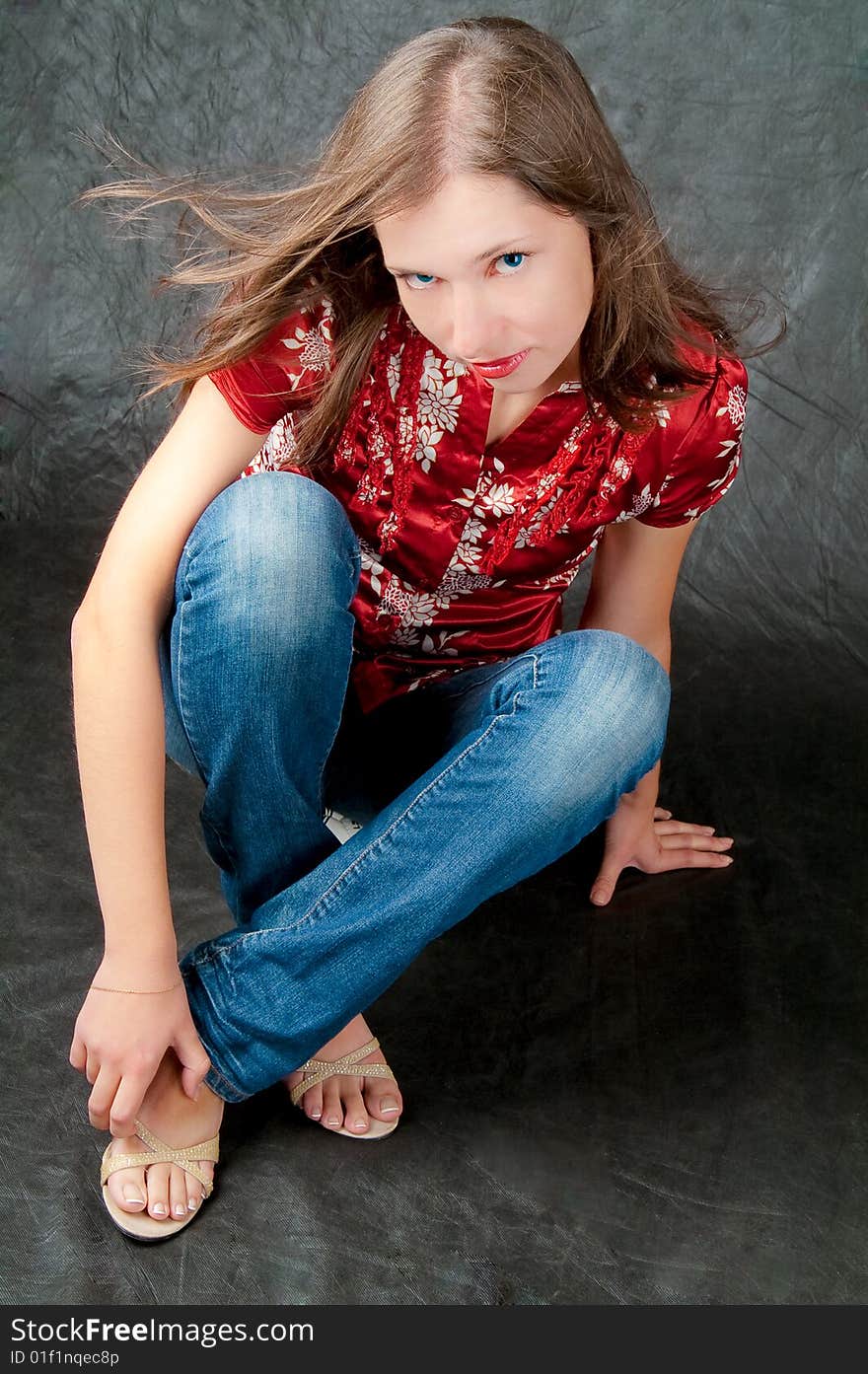 Pretty girl sitting on floor with legs crossed and looking up isolated on black background. Pretty girl sitting on floor with legs crossed and looking up isolated on black background